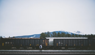 男人站在铁路附近的火车
